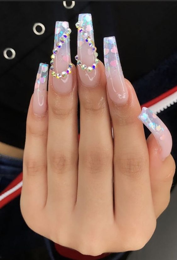 Clear nails with rhinestones on the middle finger forming a heart